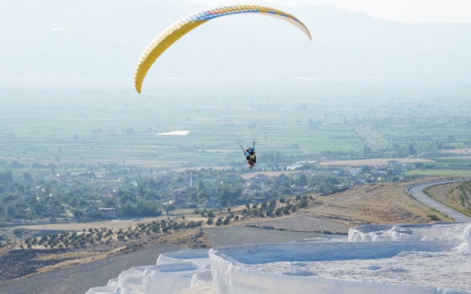 Tandem paragliding over Pamukkale's travertine terraces, Turkey.