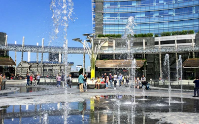 People enjoying fountains at Piazza Gae Aulenti, Milan during hop-on hop-off tour.