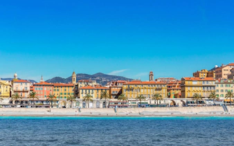 Nice beachfront with colorful buildings and palm trees, part of the Ghosts of the Riviera tour.