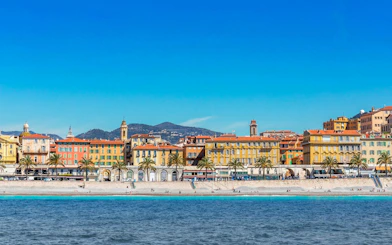 Nice beachfront with colorful buildings and palm trees, part of the Ghosts of the Riviera tour.