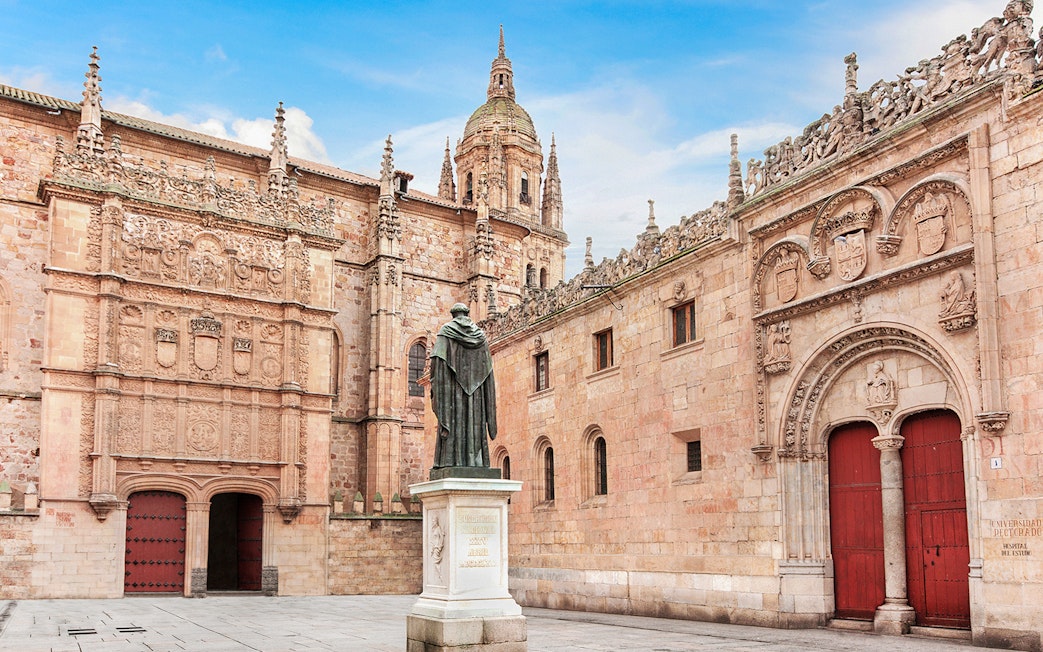 Salamanca University facade with intricate carvings and a statue in the courtyard.