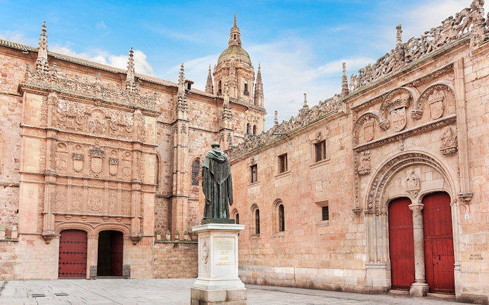 Salamanca University facade with intricate carvings and a statue in the courtyard.