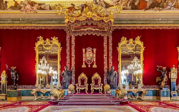 Throne room with ornate gold decor inside Royal Palace of Madrid.