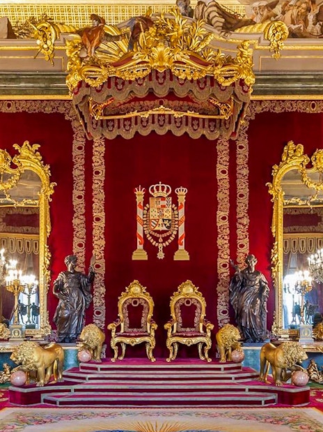 Throne room with ornate gold decor inside Royal Palace of Madrid.