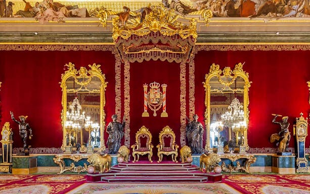 Throne room with ornate gold decor inside Royal Palace of Madrid.