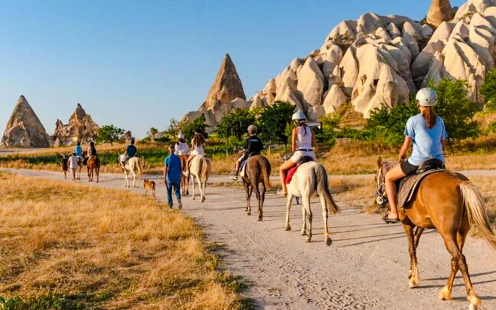 Guests on horseback during sunrise tour in Cappadocia with rock formations in view.