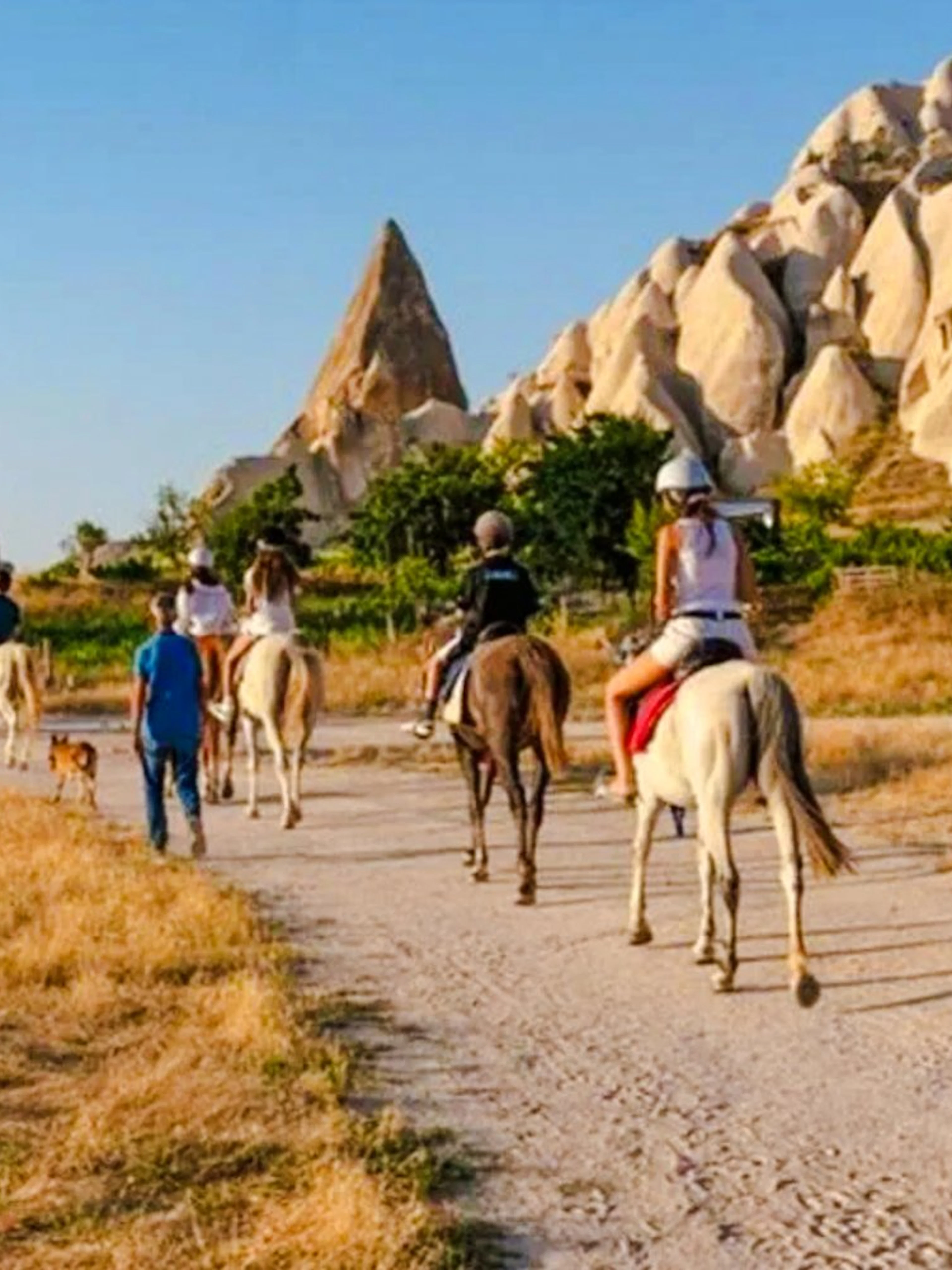 Guests on horseback during sunrise tour in Cappadocia with rock formations in view.