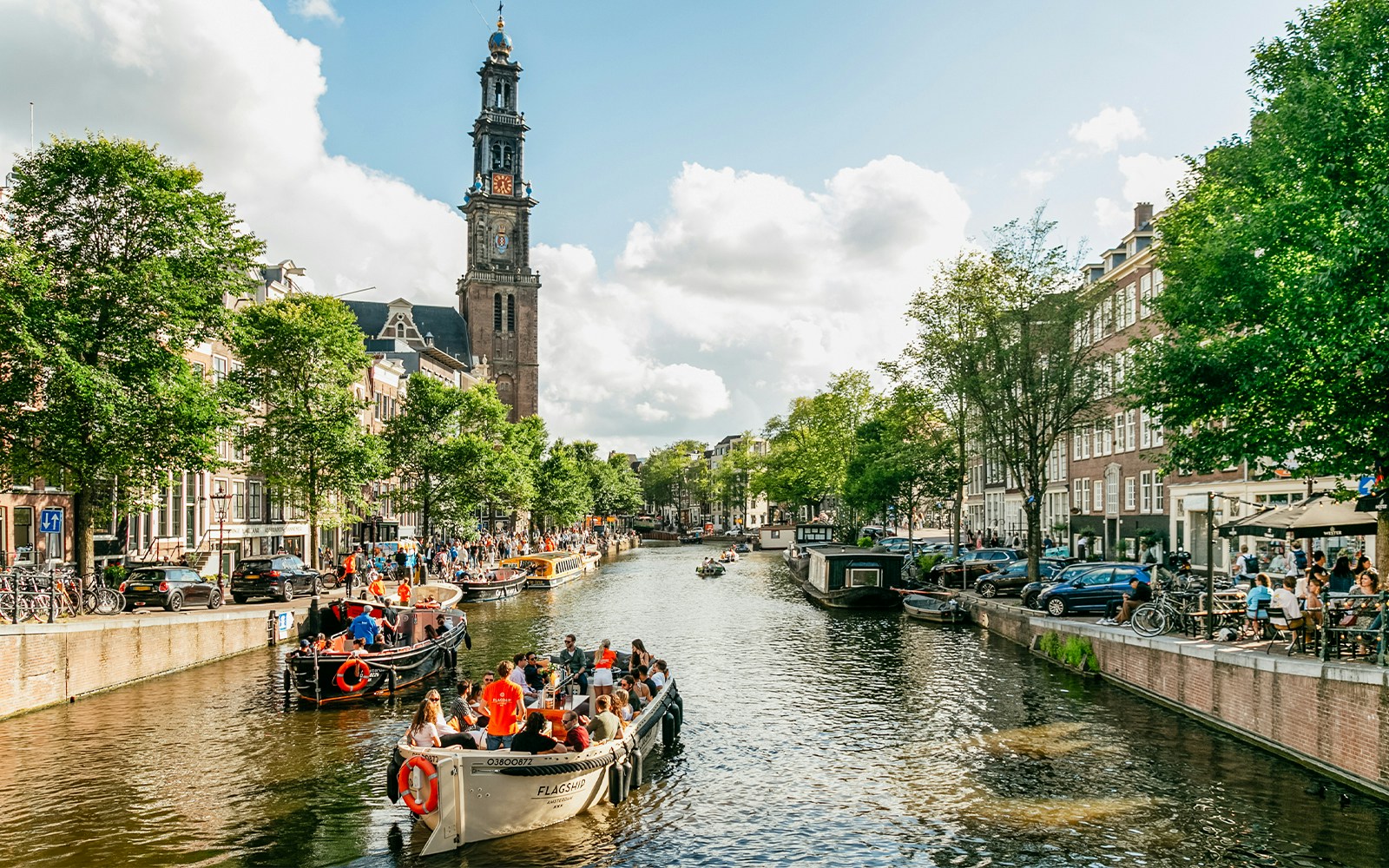 Evening canal cruise in Amsterdam with passengers enjoying views from a luxury boat.