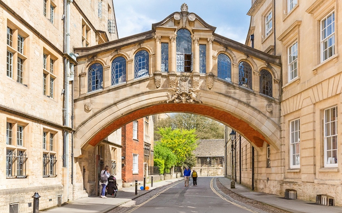 Bridge of Sighs over a street in Oxford, England, with pedestrians walking below.