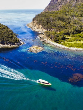 Boat navigating through the clear waters of Bruny Island coastline.