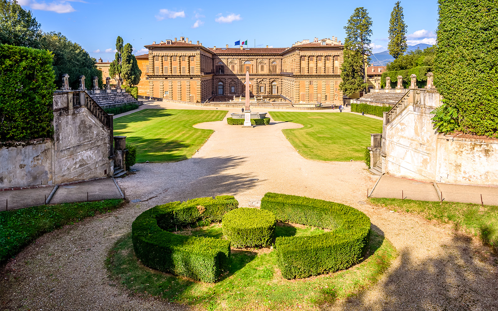 Boboli Gardens with Pitti Palace in Florence, featuring manicured hedges and a central obelisk.