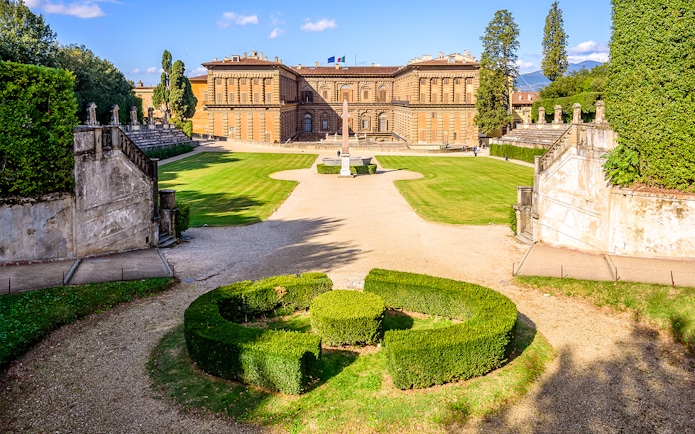 Boboli Gardens with Pitti Palace in Florence, featuring manicured hedges and a central obelisk.