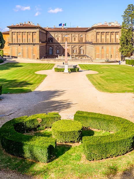 Boboli Gardens with Pitti Palace in Florence, featuring manicured hedges and a central obelisk.
