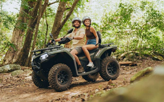 Couple riding quad bike through forest on Bel Ombre tour.