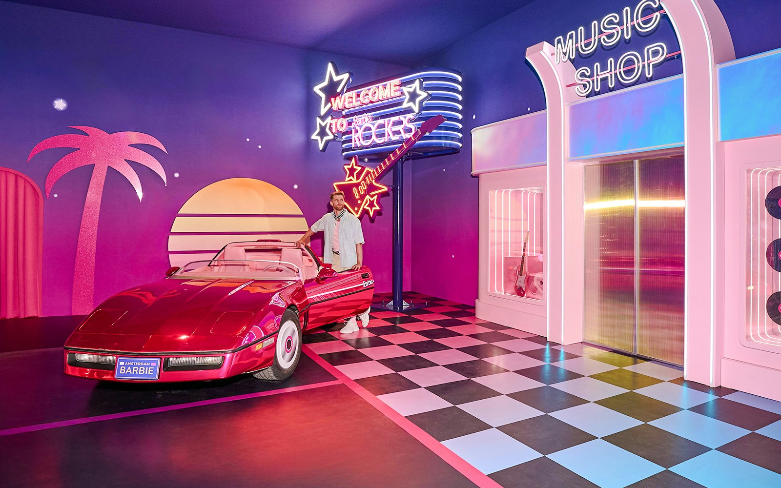 Ken at Barbie The Dream Experience in Amsterdam with a red convertible and neon signs.