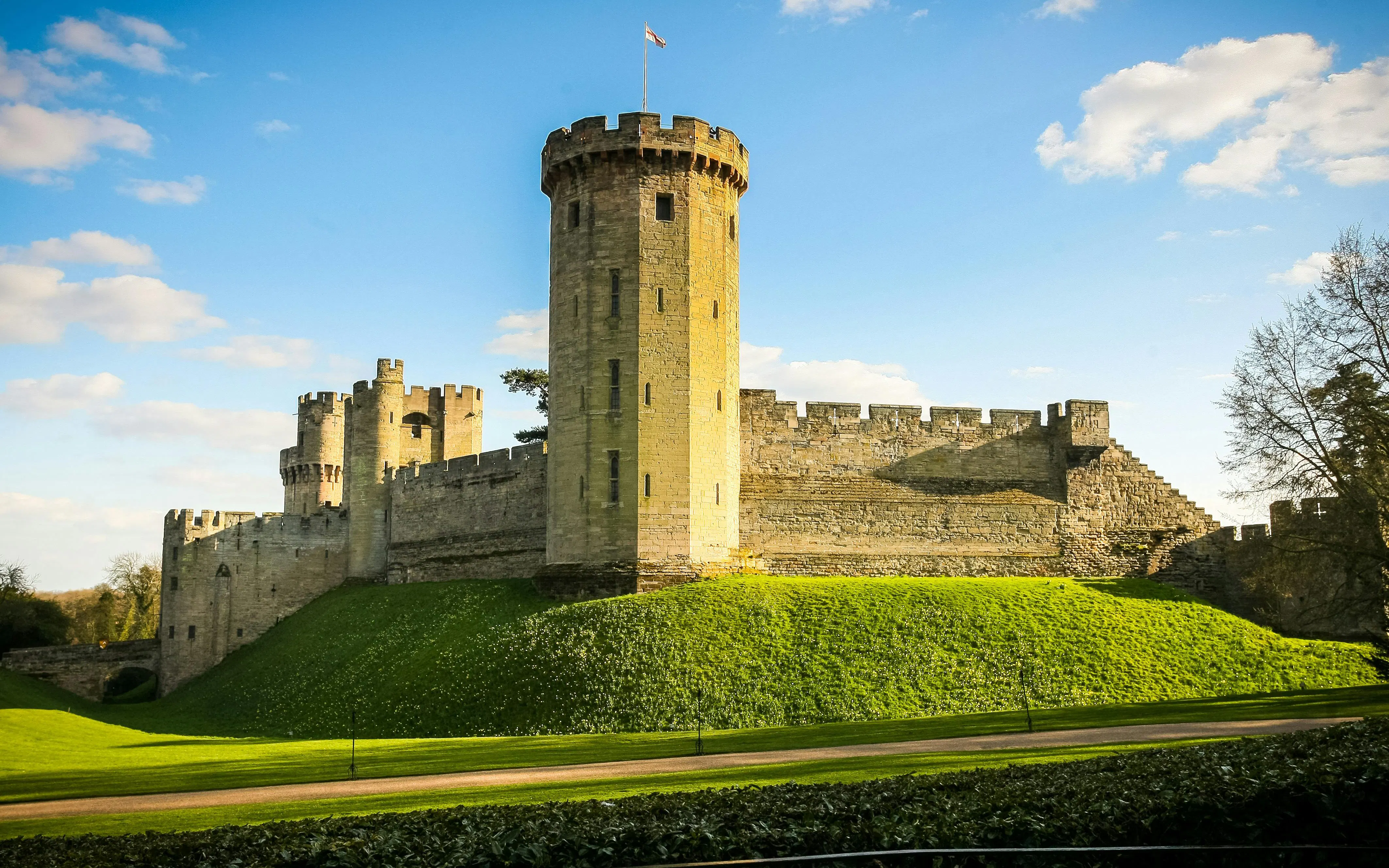 Warwick Castle stone tower and walls under a blue sky.