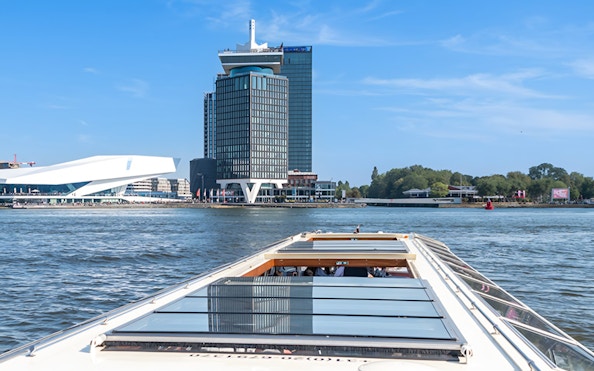 Canal boat cruising past A'DAM Tower and Eye Film Museum in Amsterdam.