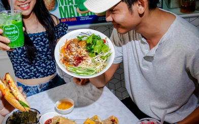 People enjoying Vietnamese cuisine with a bowl of salad and banh mi in Da Nang.