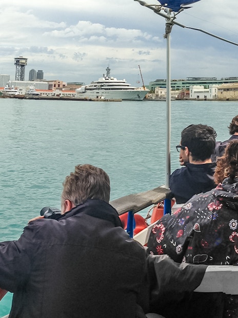 Tourists on Las Golondrinas boat viewing Barcelona skyline with W Hotel in background.