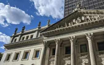 Flatiron Building facade with classical statues under a blue sky, New York City.