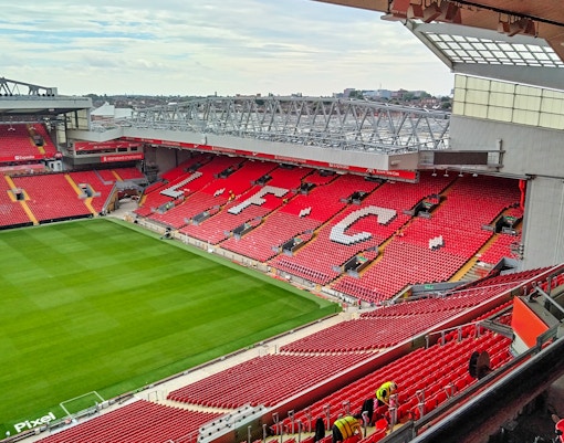 Liverpool FC stadium with red seats and field, view from the stands.