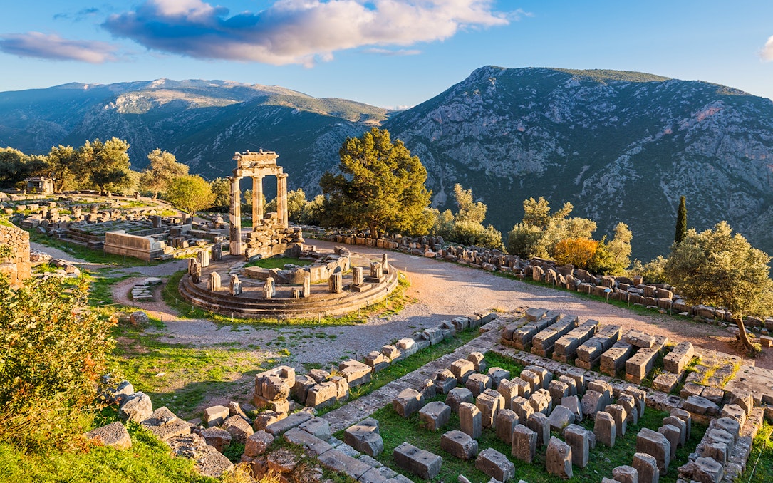 Temple of Athena Pronaia ruins with mountain backdrop in Delphi, Greece.