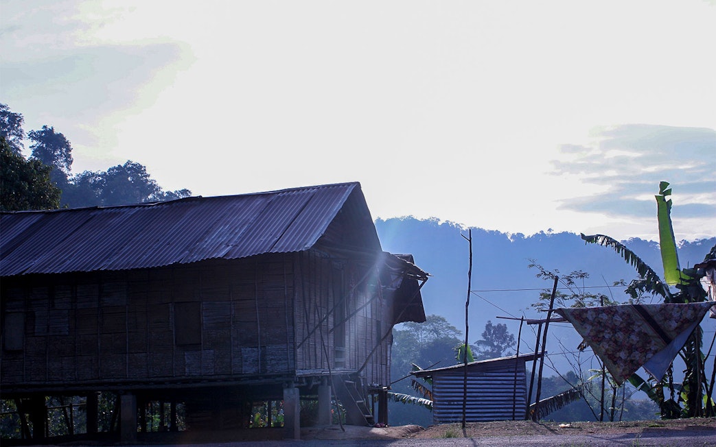 Traditional wooden house in Cameron Highlands with misty hills in the background.