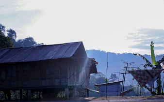 Traditional wooden house in Cameron Highlands with misty hills in the background.