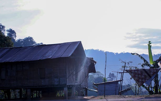 Traditional wooden house in Cameron Highlands with misty hills in the background.
