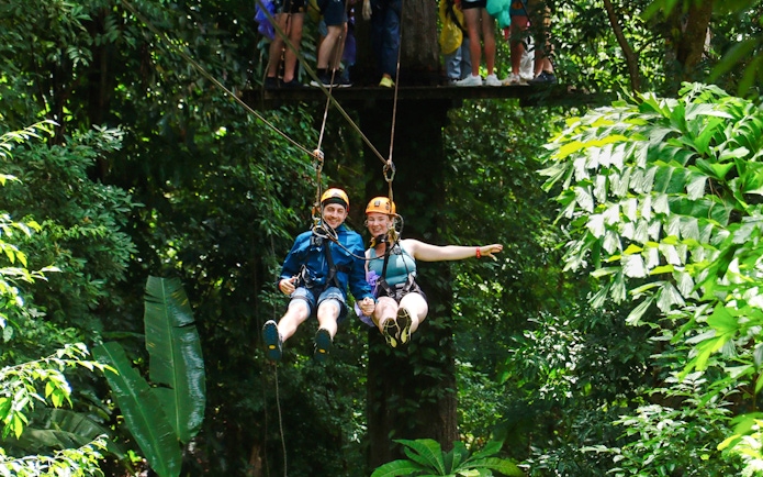 Two people ziplining through lush jungle at Flying Hanuman, Phuket.
