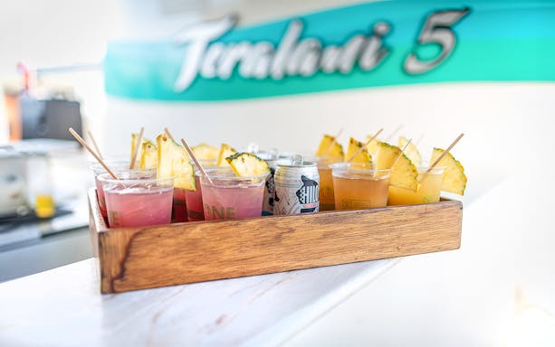 Drinks with pineapple slices on a tray aboard a luxury catamaran in Lahaina.