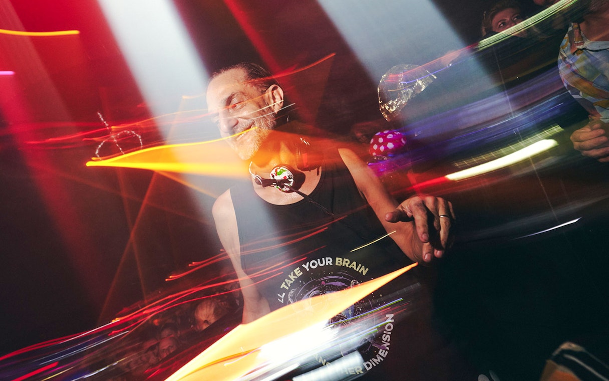 DJ performing at Club Chinois with vibrant lights and crowd.