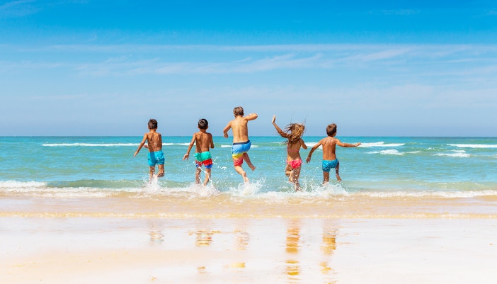 Children running into the sea at Formentor Beach, Mallorca, during a boat trip.