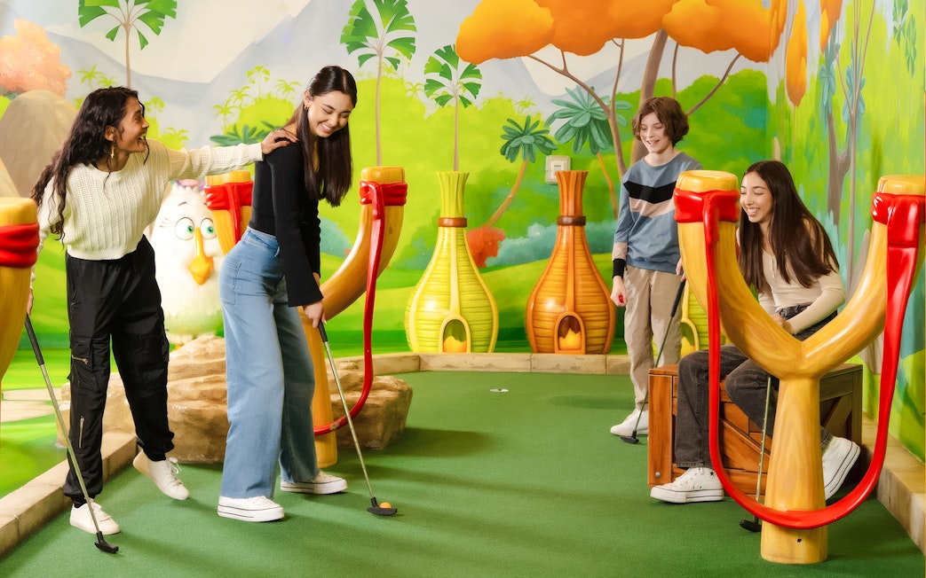 Group playing mini golf at Angry Birds Mini Golf, American Dream, with colorful slingshot obstacles.