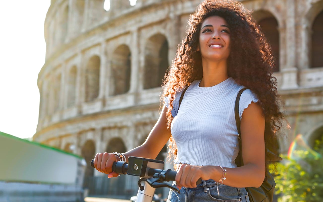 Woman on e-scooter near the Colosseum in Rome, Italy.