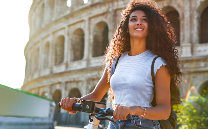 Woman on e-scooter near the Colosseum in Rome, Italy.
