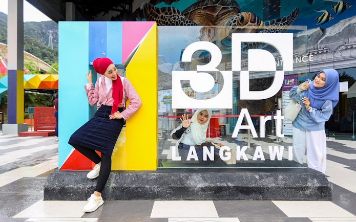 Women posing at 3D Art Langkawi entrance.