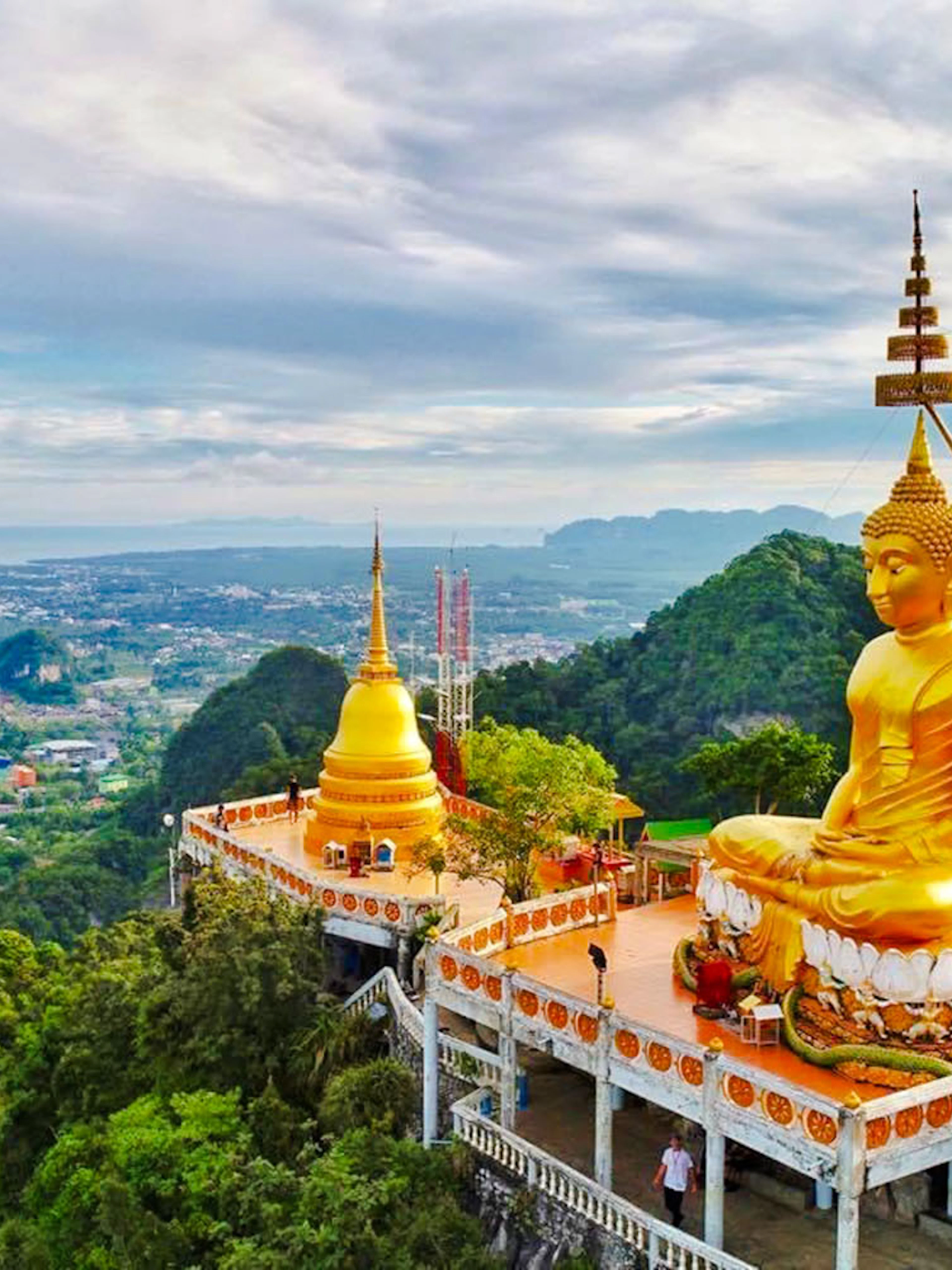 Buddha statue overlooking lush landscape at Tiger Cave Temple, Krabi, Thailand.
