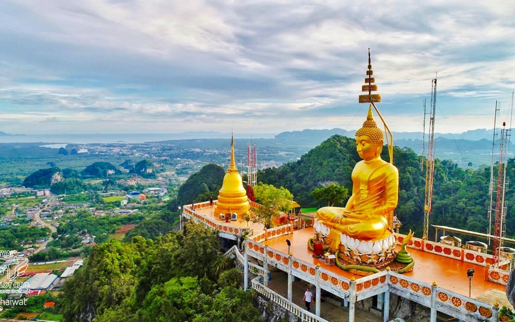 Buddha statue overlooking lush landscape at Tiger Cave Temple, Krabi, Thailand.
