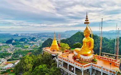 Buddha statue overlooking lush landscape at Tiger Cave Temple, Krabi, Thailand.