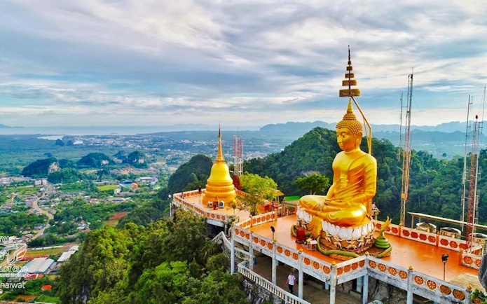 Buddha statue overlooking lush landscape at Tiger Cave Temple, Krabi, Thailand.