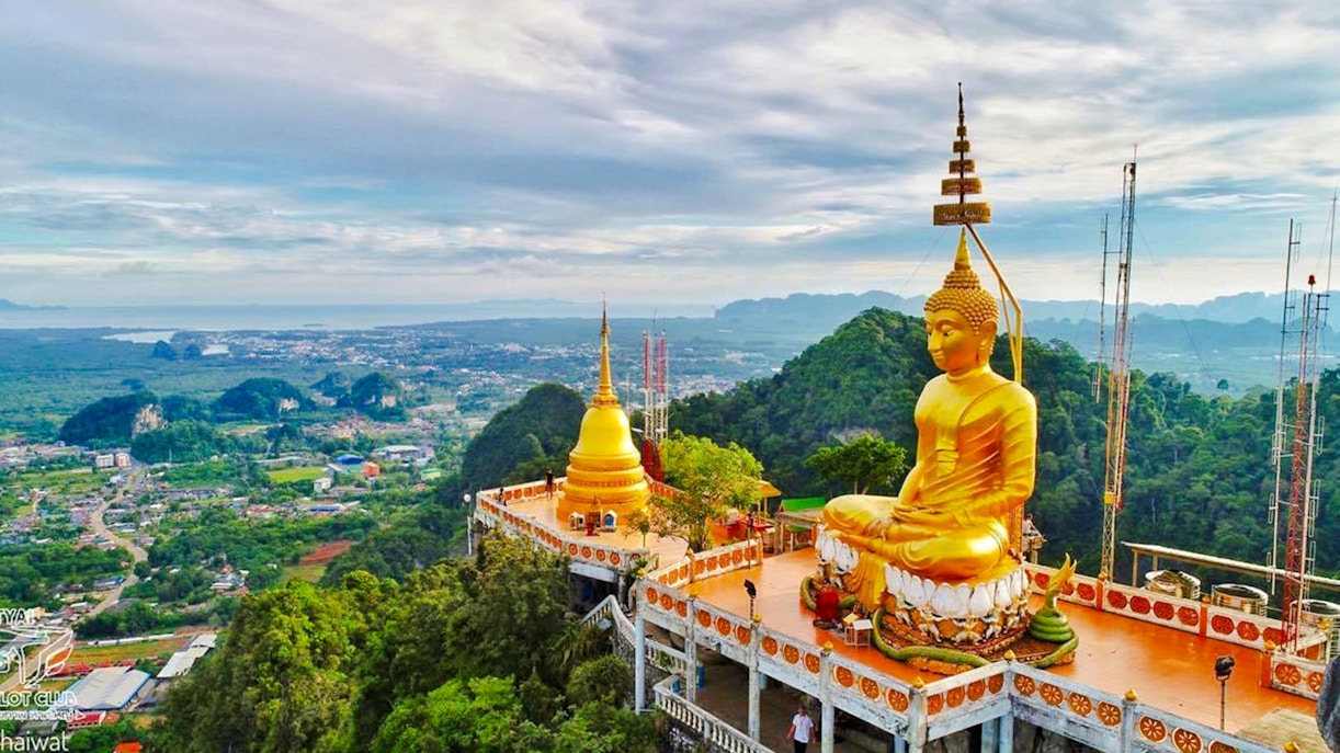 Buddha statue overlooking lush landscape at Tiger Cave Temple, Krabi, Thailand.
