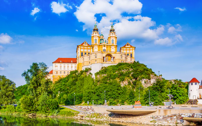 Melk Abbey exterior with baroque architecture in Vienna, surrounded by lush greenery.