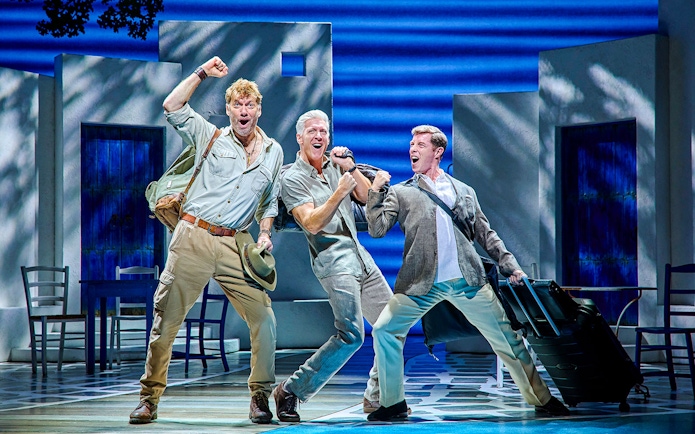 Three actors performing energetically on stage in a Mamma Mia production.