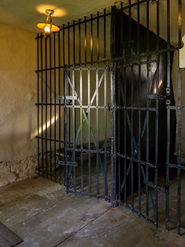 Open cell door at Old Jail Museum with iron bars and dim lighting.
