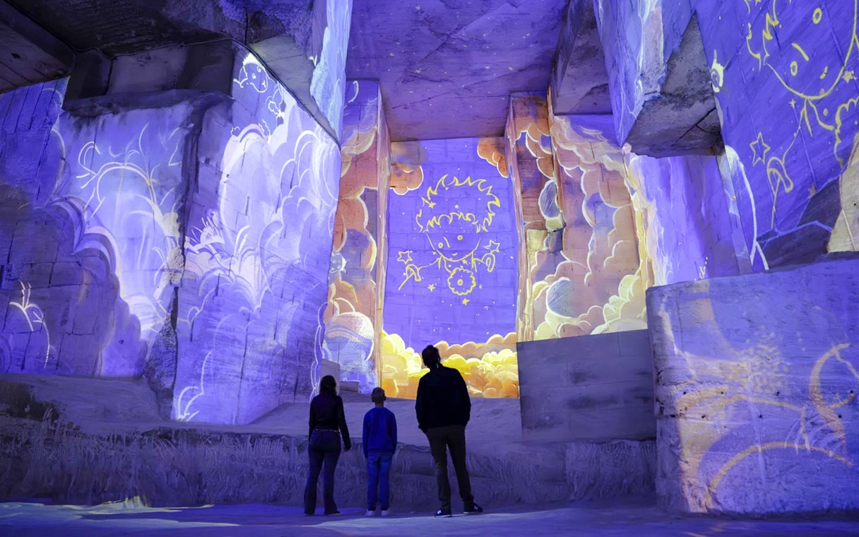 Visitors viewing Little Prince projections at Carrières des Lumières exhibition.