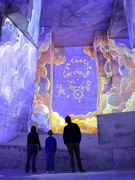 Visitors viewing Little Prince projections at Carrières des Lumières exhibition.
