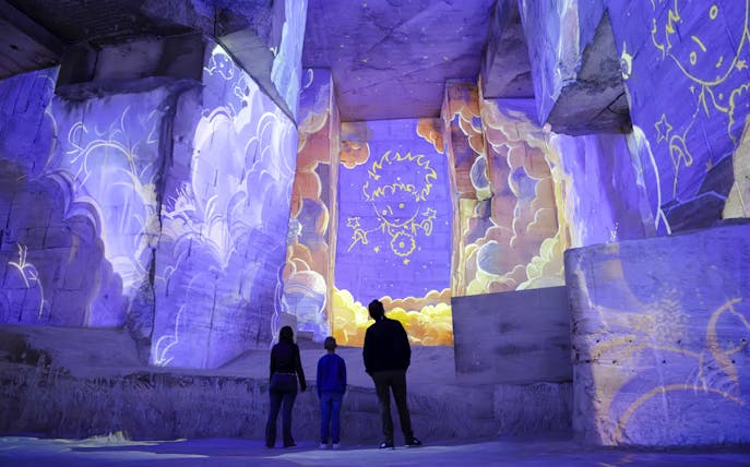 Visitors viewing Little Prince projections at Carrières des Lumières exhibition.