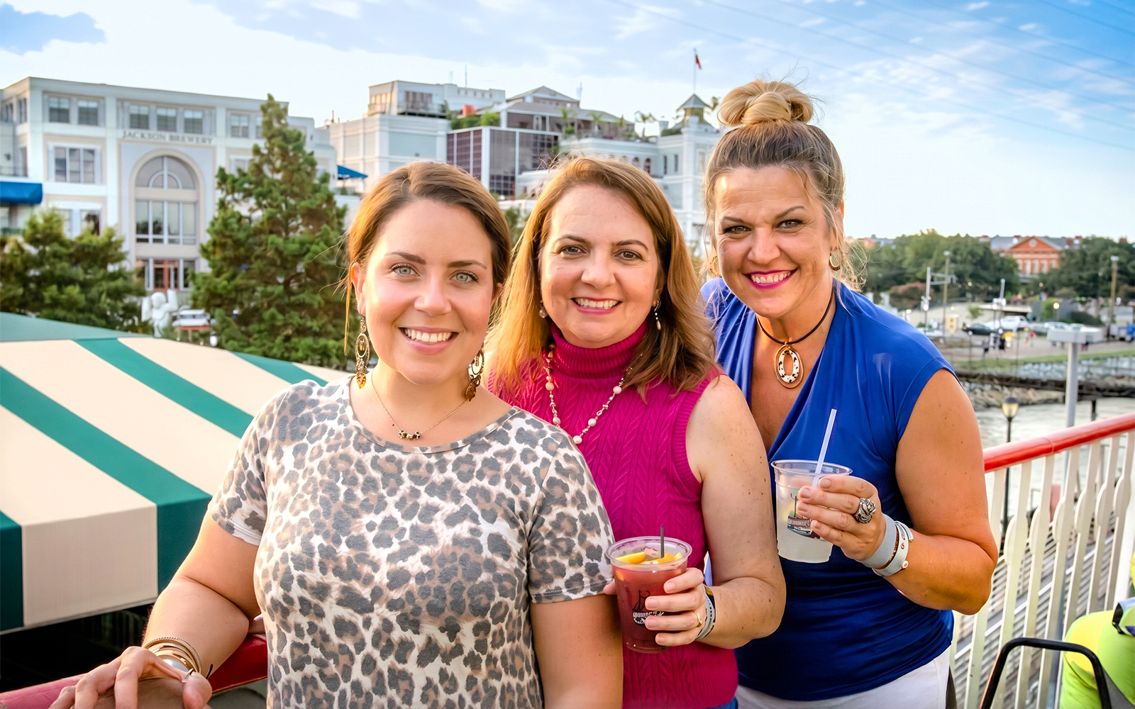 Group enjoying drinks on the Riverboat City of New Orleans with cityscape in background.