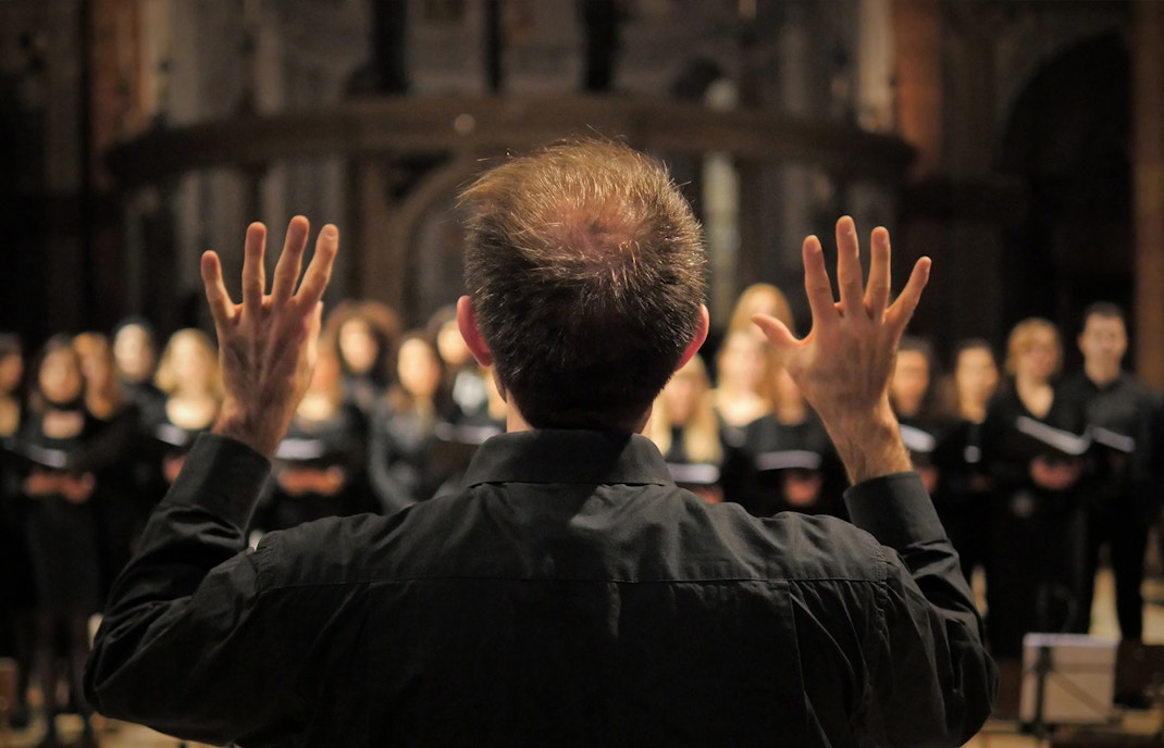 Choir conductor leads performance in cathedral.